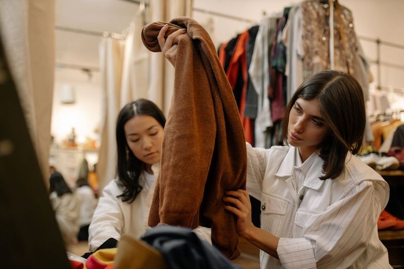 Två vänner tittar på kläder i en second hand-butik